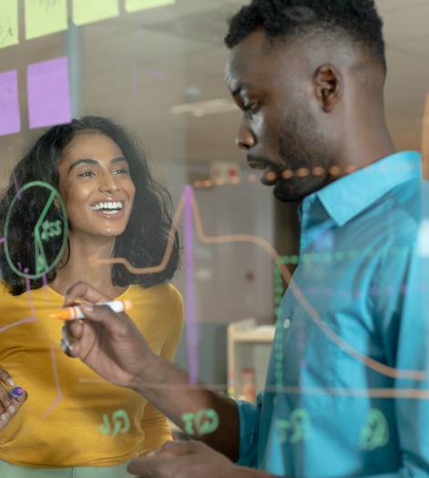 Happy multiracial colleagues planning strategy on glass wall at modern workplace. unaltered, business, teamwork and modern office concept.